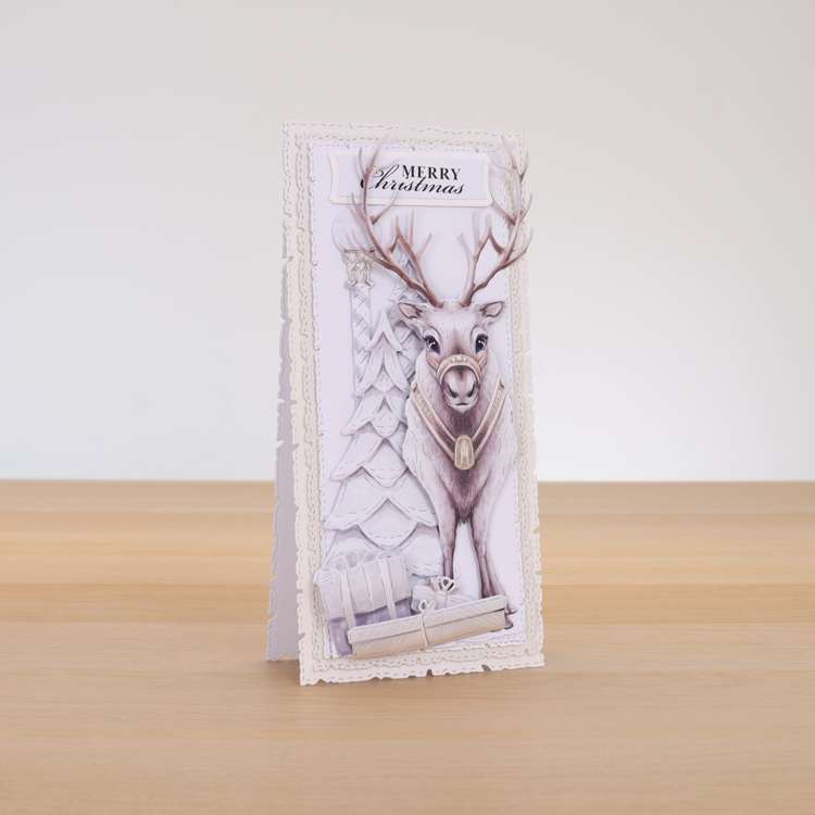 Card made using ready For A White Christmas Special Edition Vignette with a reindeer stood over presents and pine tree in the background